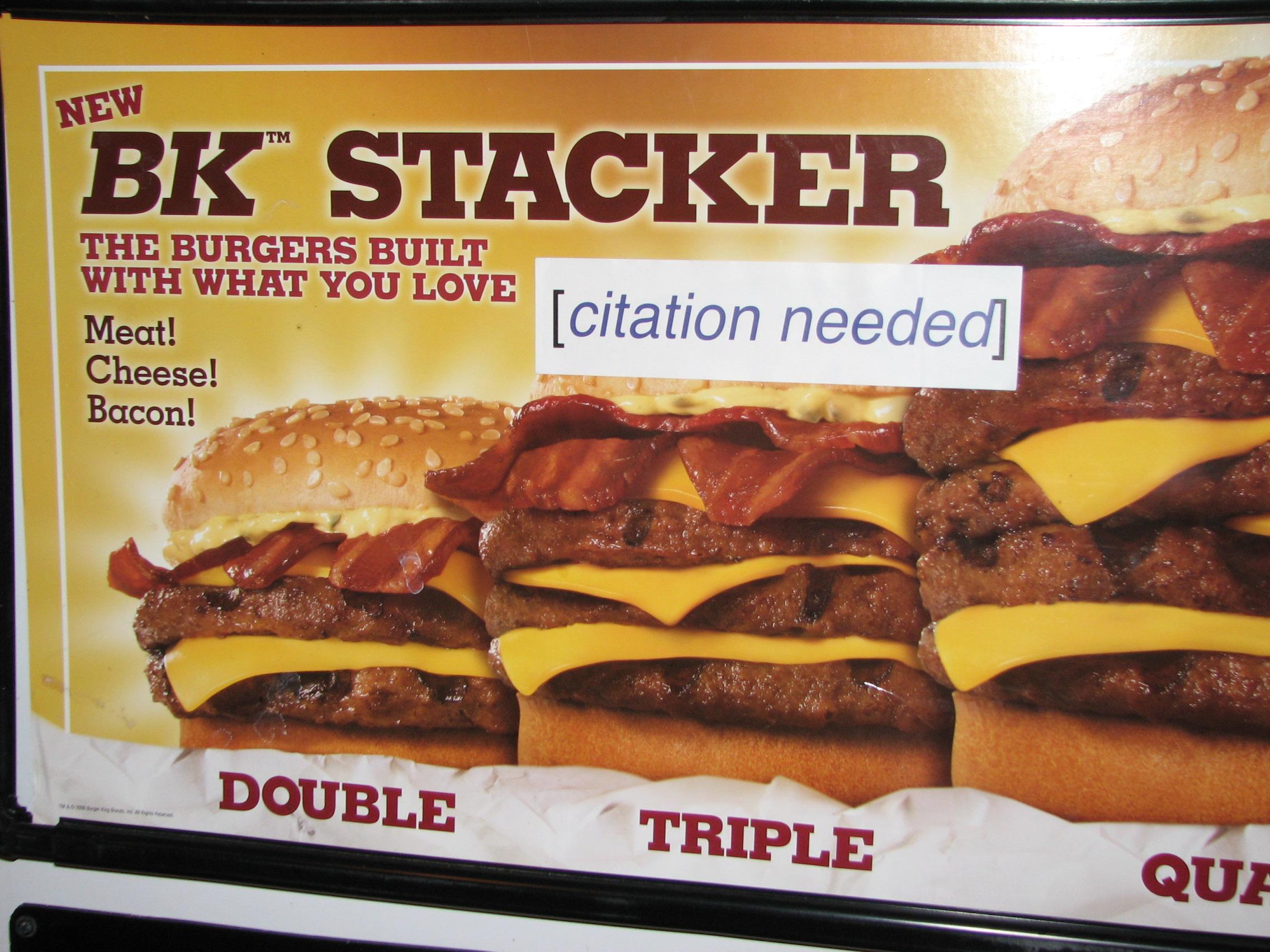 Panneau publicitaire représentant un burger. La publicité comporte un texte vantant les mérites du burger. Un autocollant avec le texte « citation needed » a été collé sur la publicité, à la suite du texte.