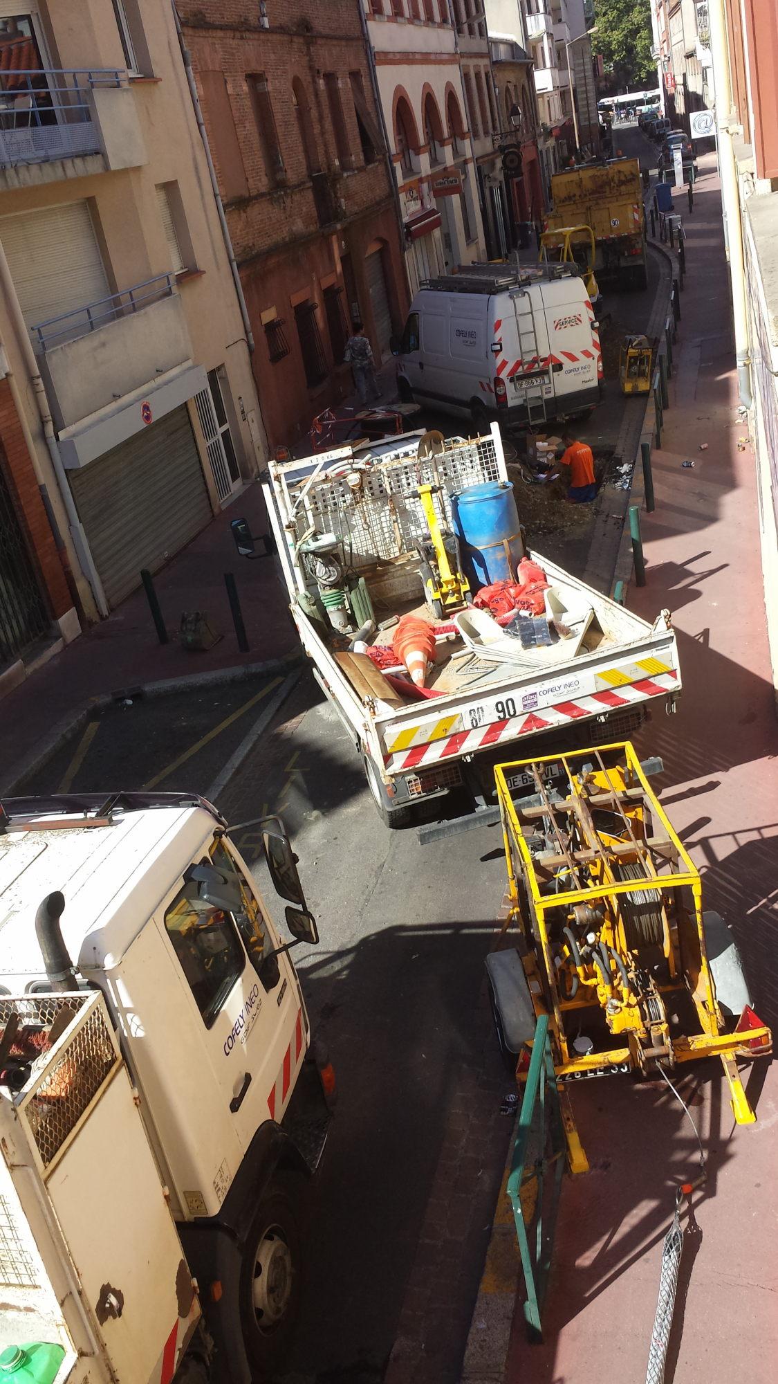 A city street blocked by several vans and trucks.